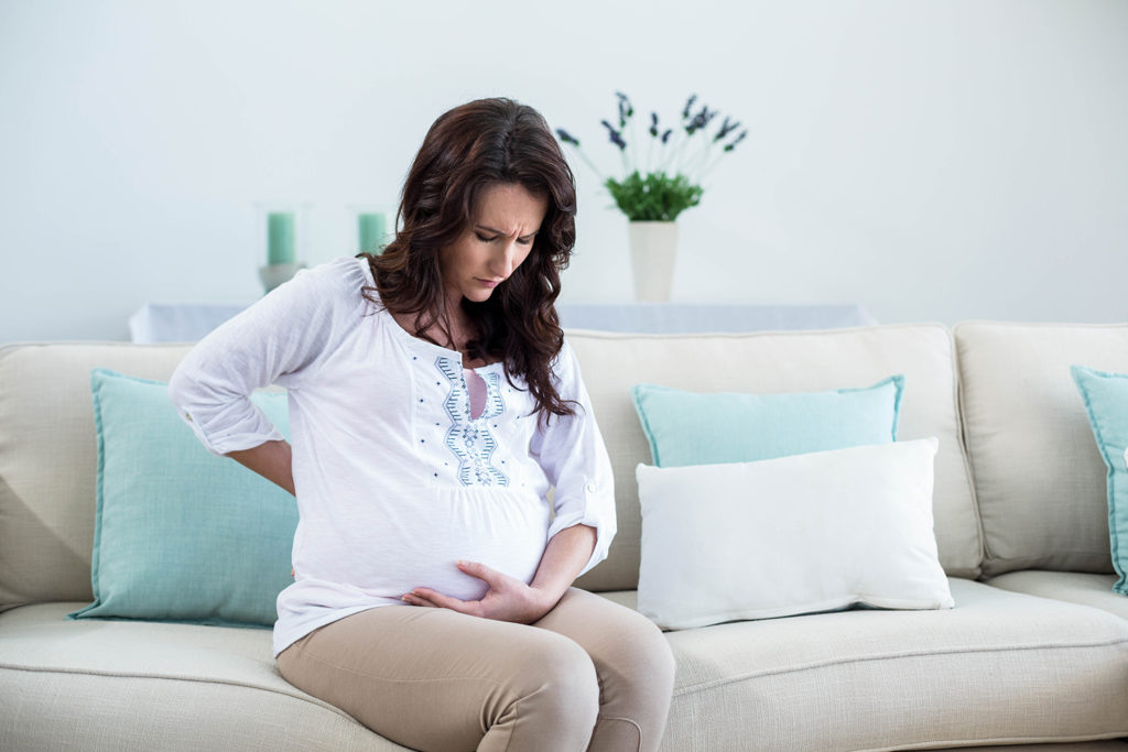 pregnant woman holding her back due to pain