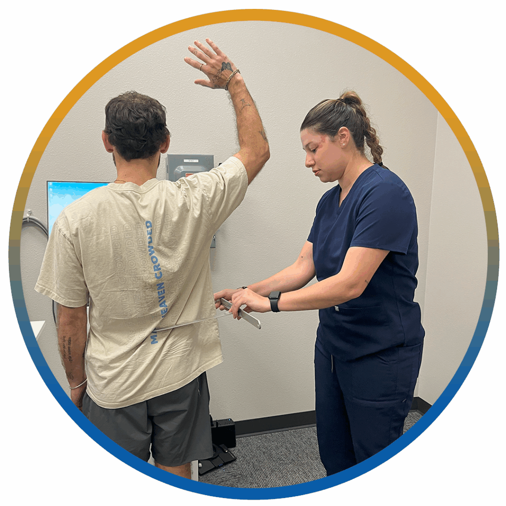 healthcare professional in navy scrubs assesses a male patient’s posture using a handheld tool in a clinical setting